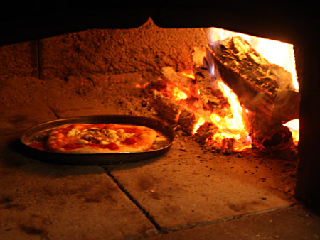 La cottura della pizza nel forno a legna